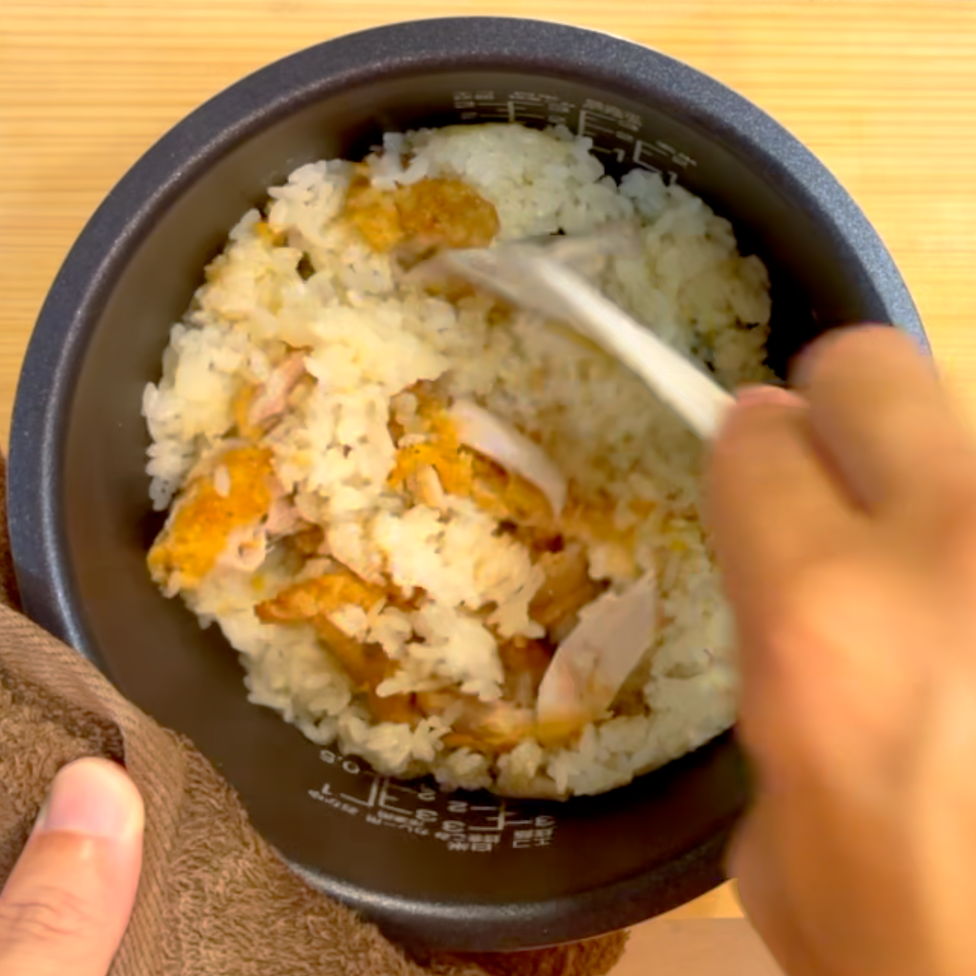 炊き上がったご飯とファミチキをほぐしながら混ぜる様子
