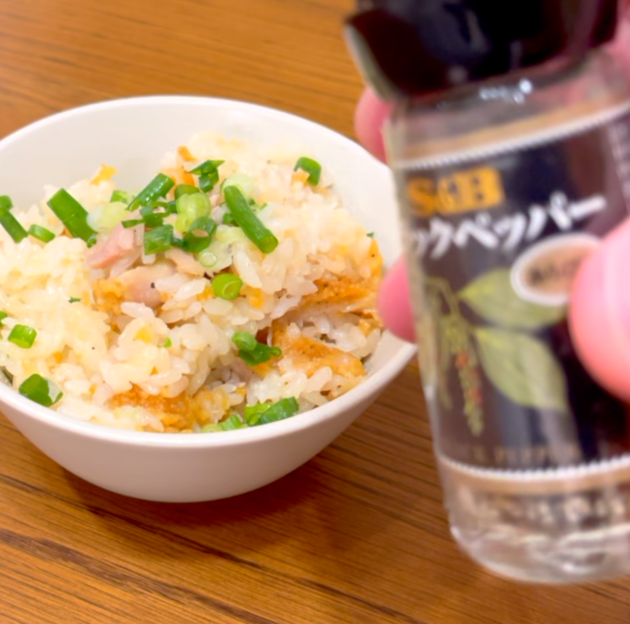 炊き込みご飯を器に盛りブラックペッパーを振る様子