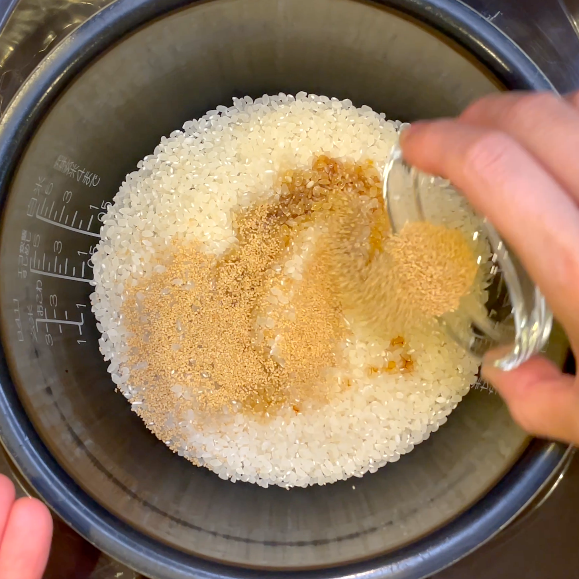 炊飯釜に米と(A)を入れ、水を規定線まで加える工程