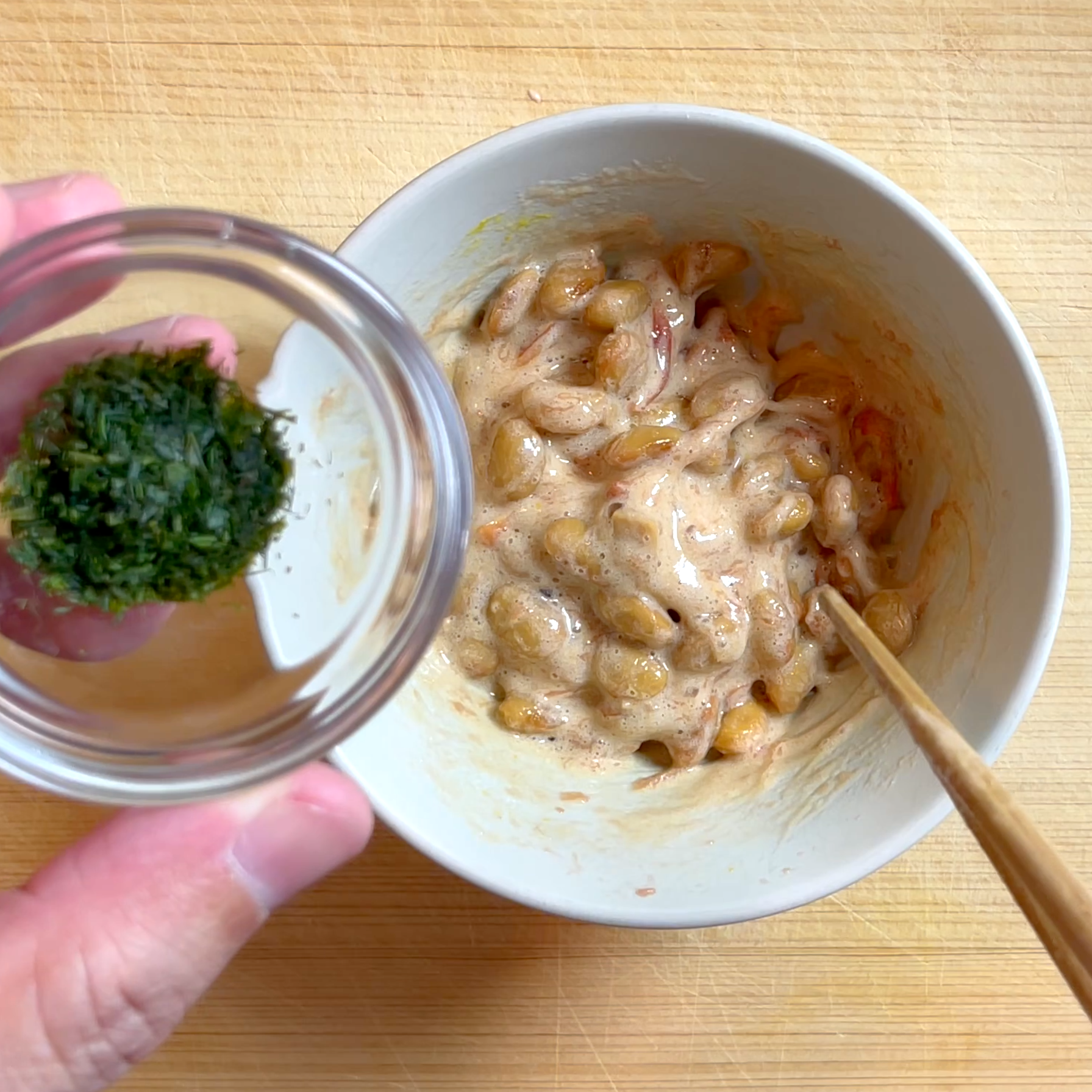 納豆にからしとタレ、あおさのりを加えて混ぜる工程