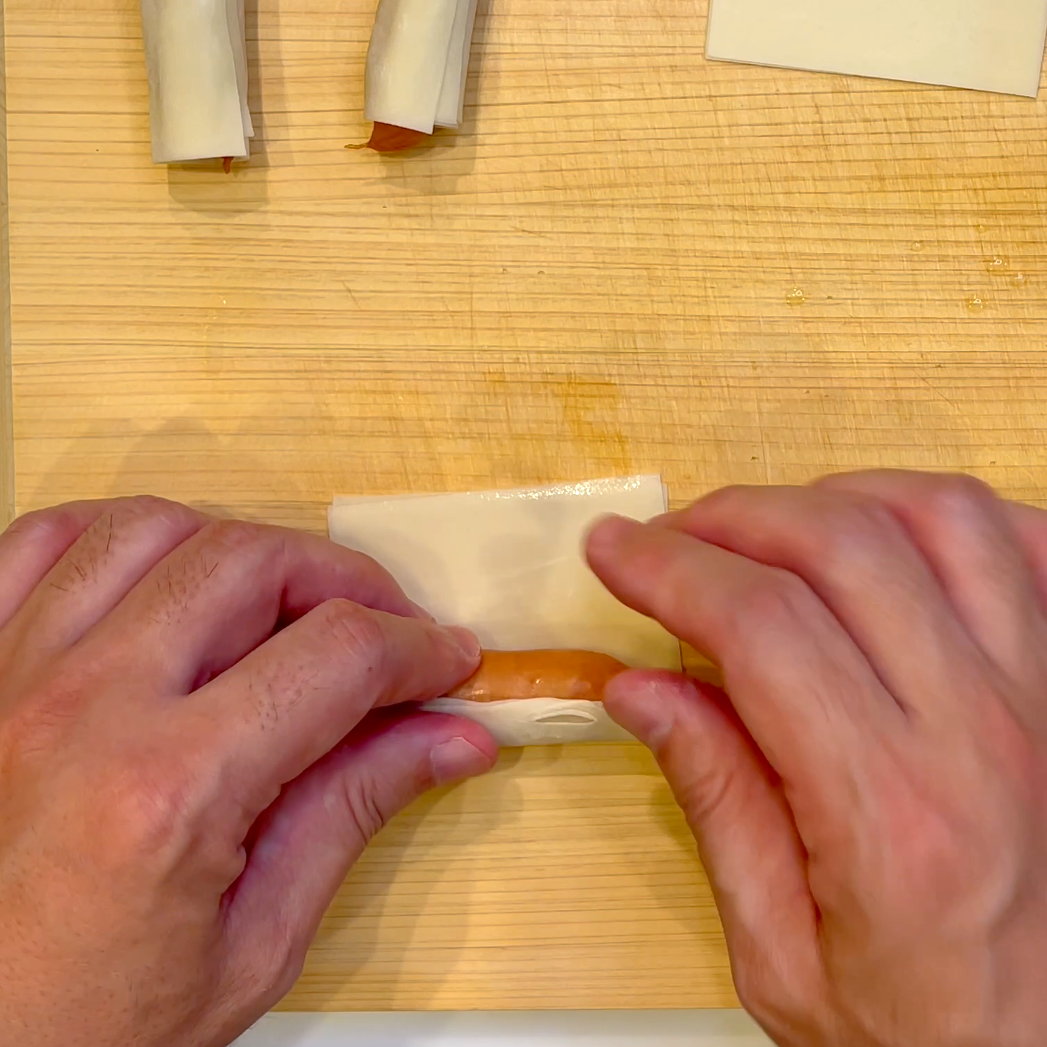 ワンタンの皮を重ねてウインナーに巻く工程