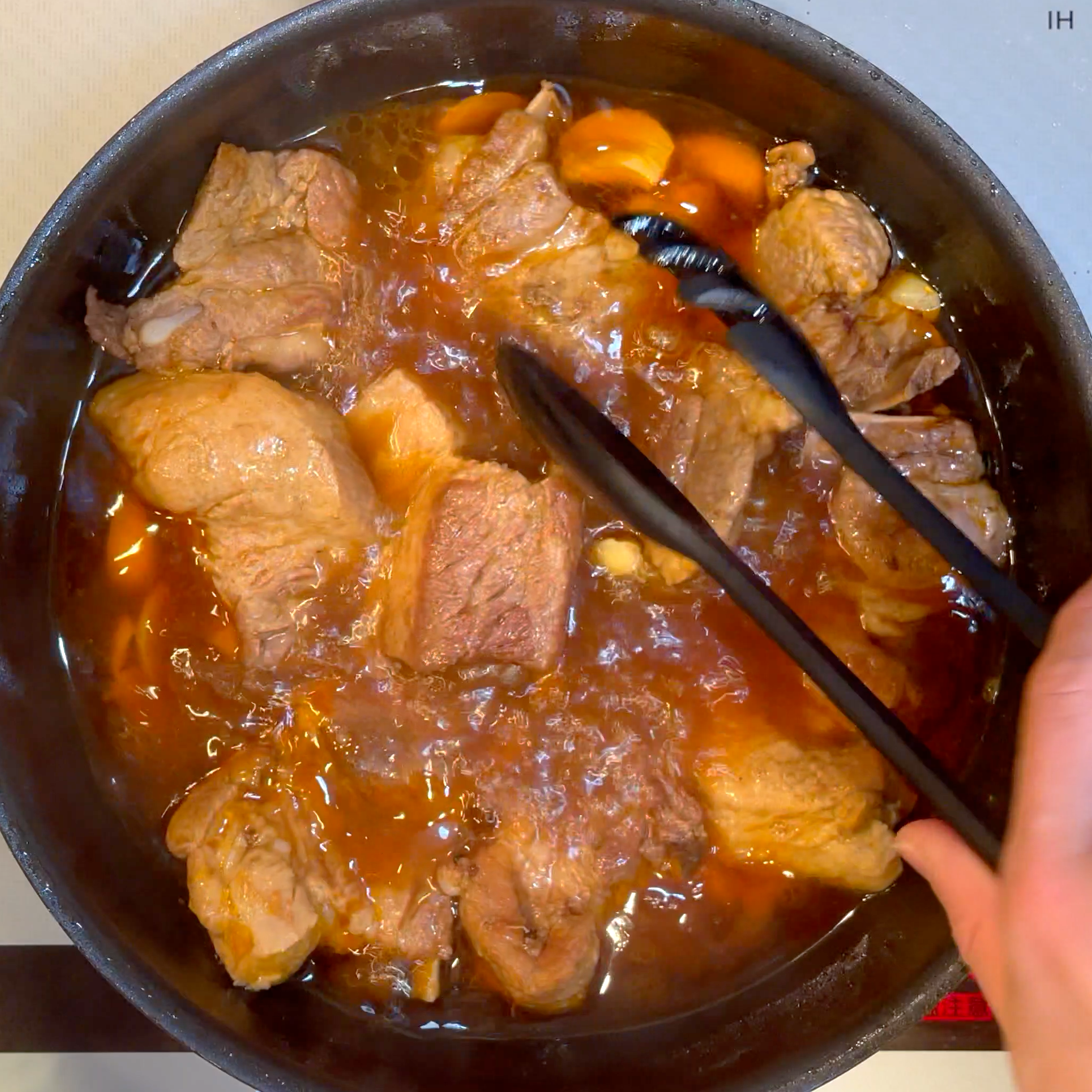 調味料とにんにくを加えてスペアリブを煮込む工程