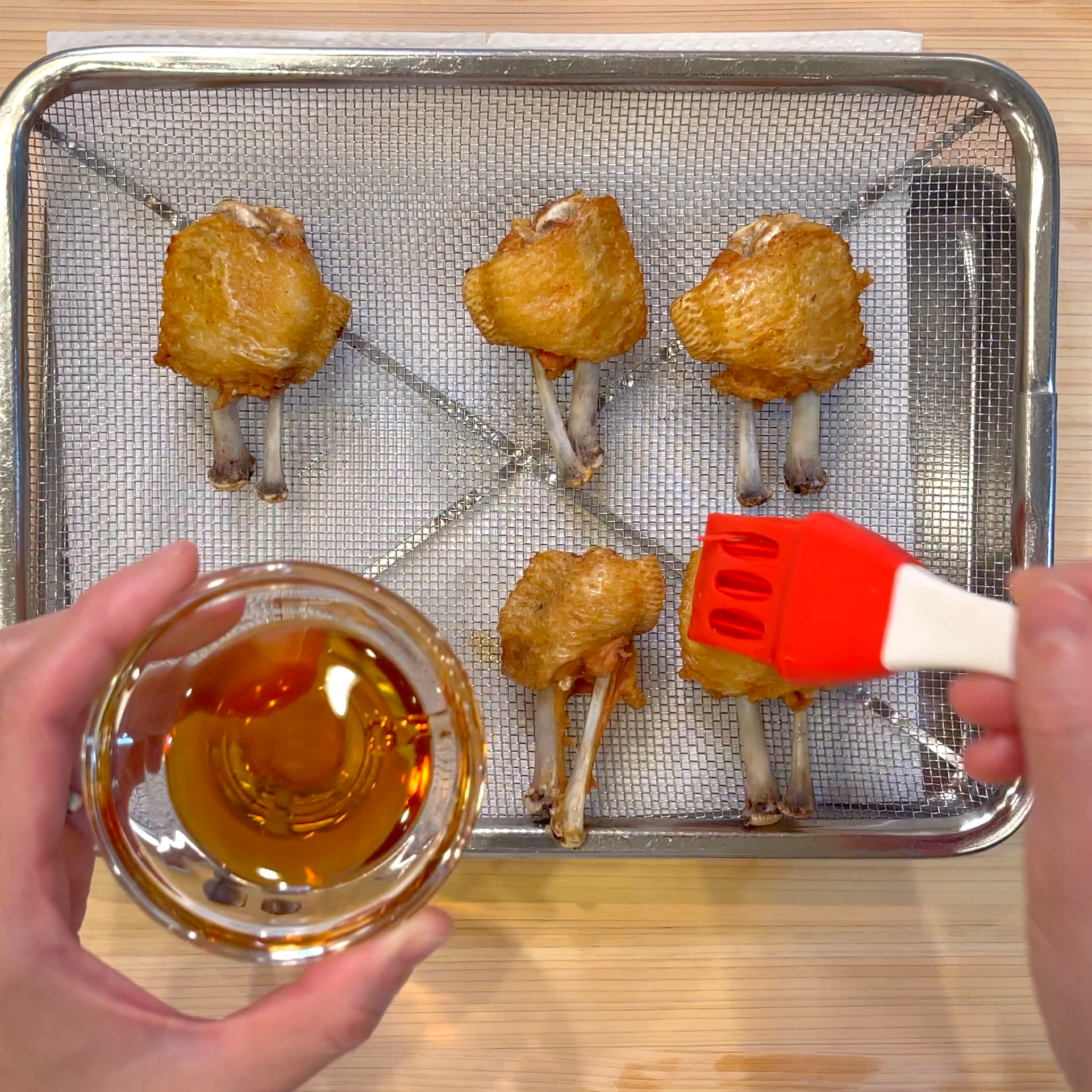 揚げた手羽先にごま油を塗って塩をかける工程