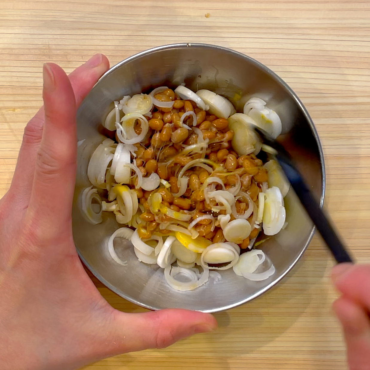 納豆にねぎとタレとからしを入れて混ぜる工程