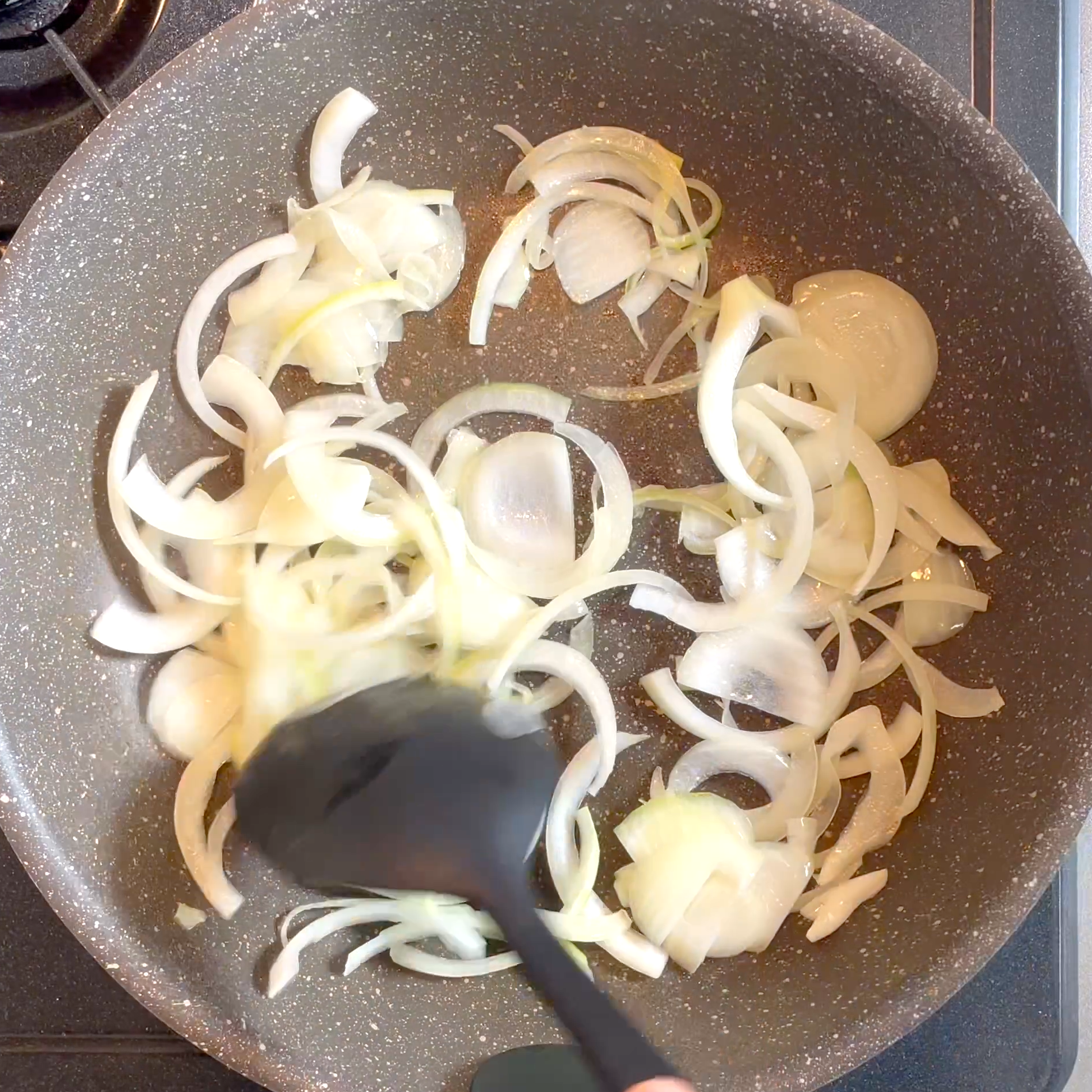 サラダ油を熱したフライパンで玉ねぎを炒める工程