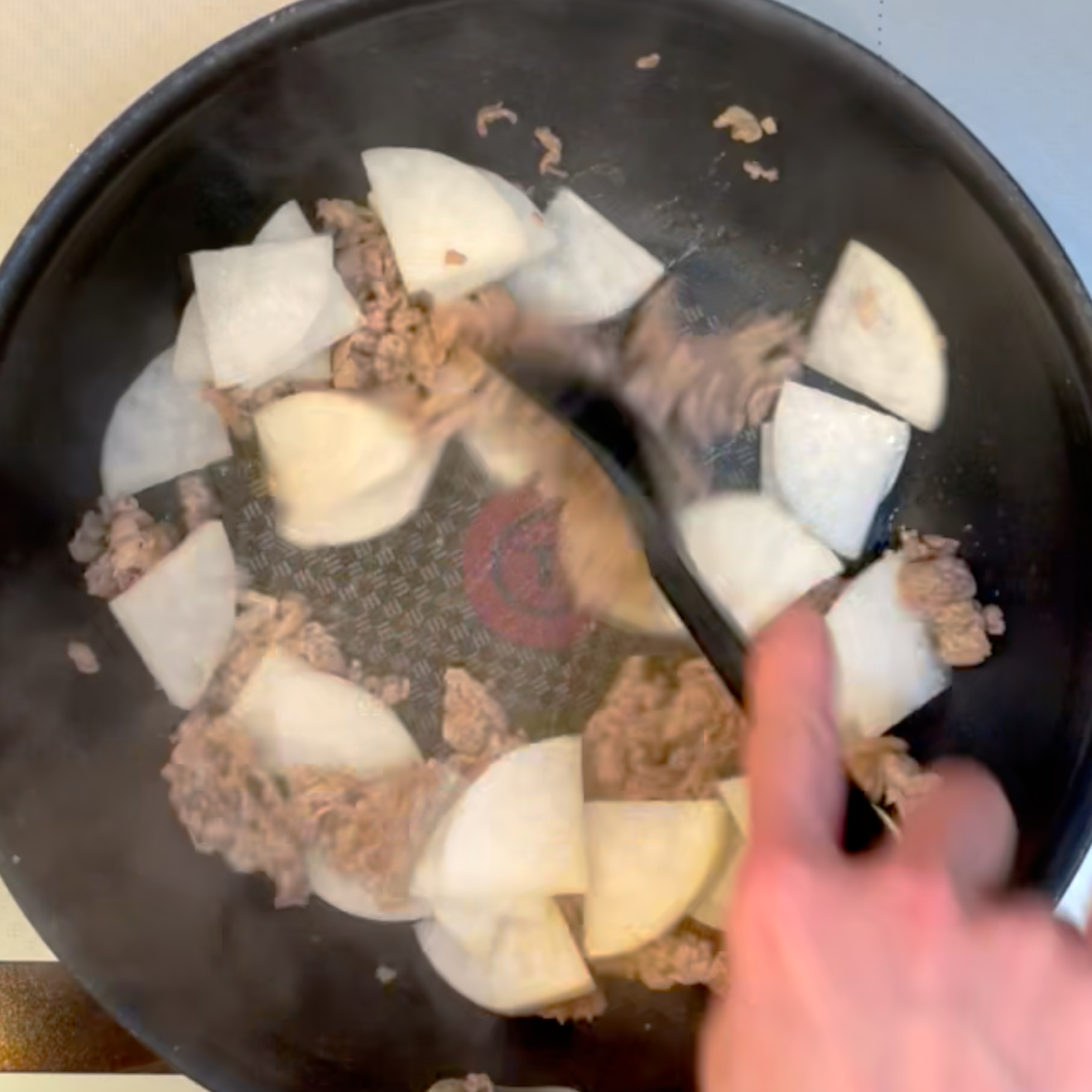 牛肉と大根を調味料と一緒に炒める工程