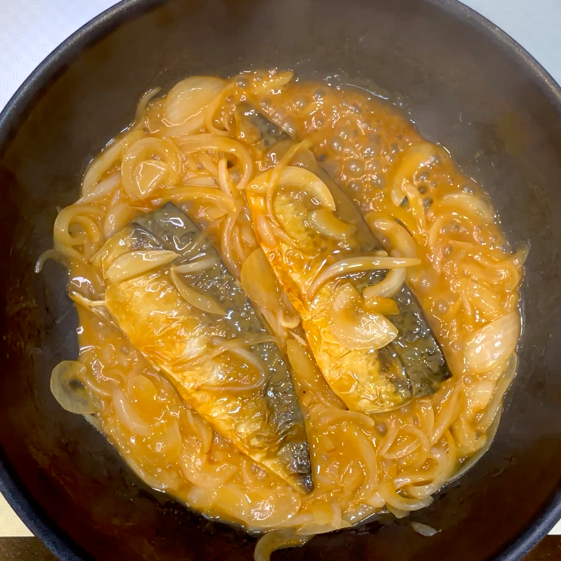 サバと玉ねぎにタレを加えて絡め煮詰める工程