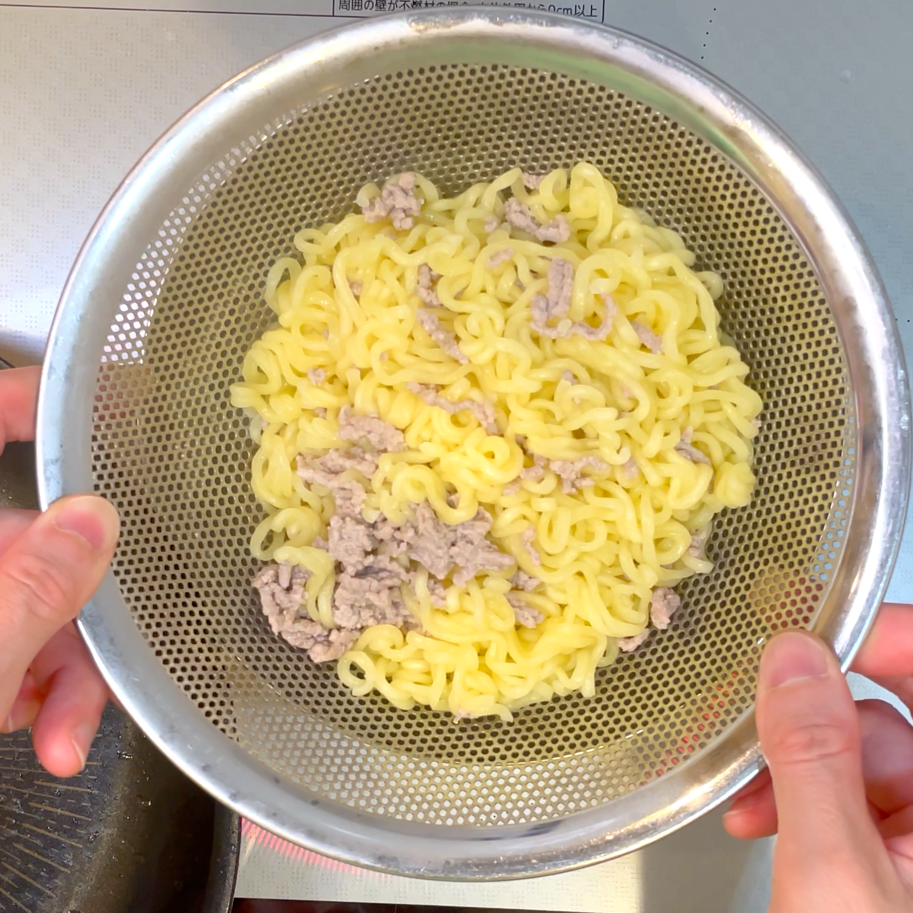 麺をざるにあげて水気を切る工程