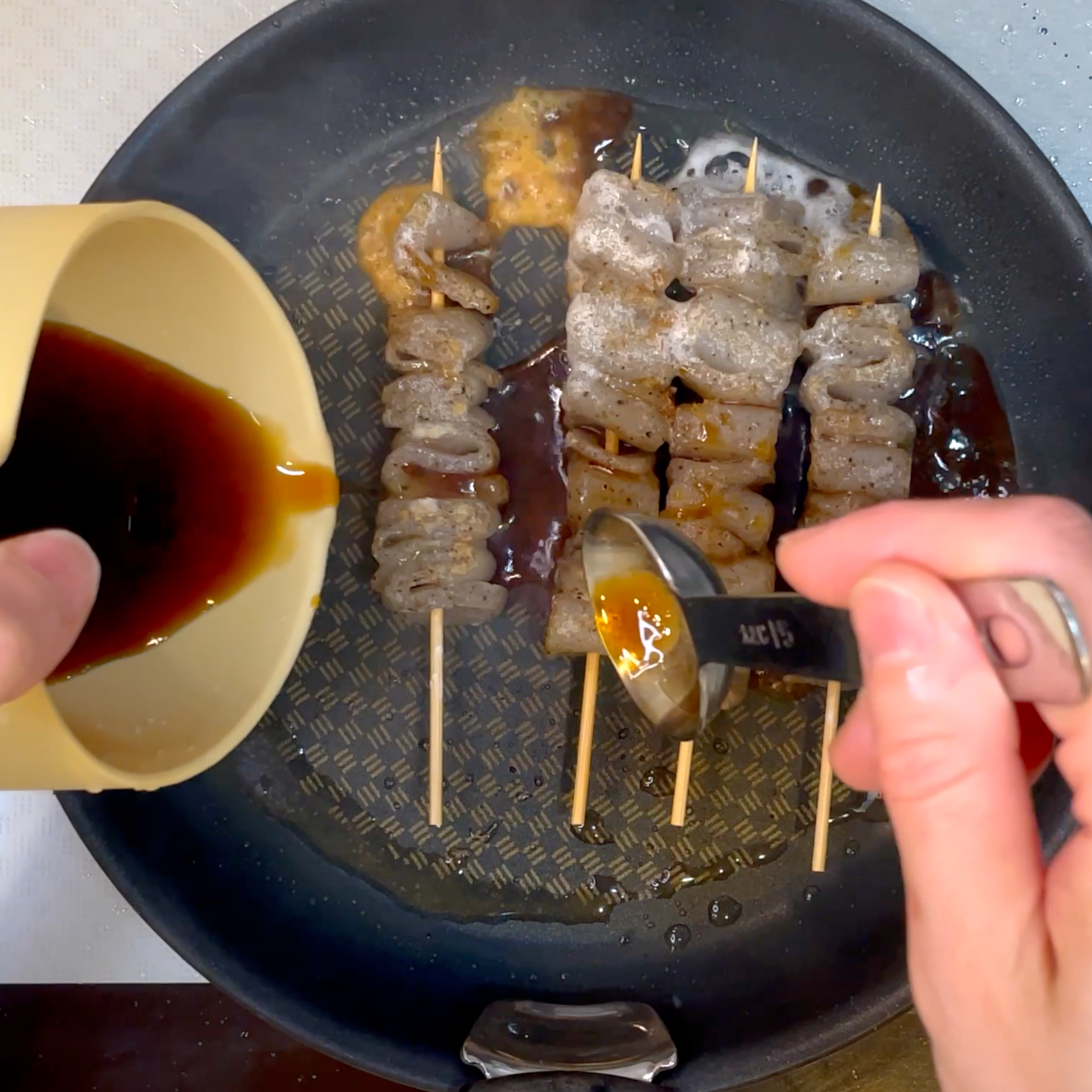 タレを加えてこんにゃく串に絡める工程