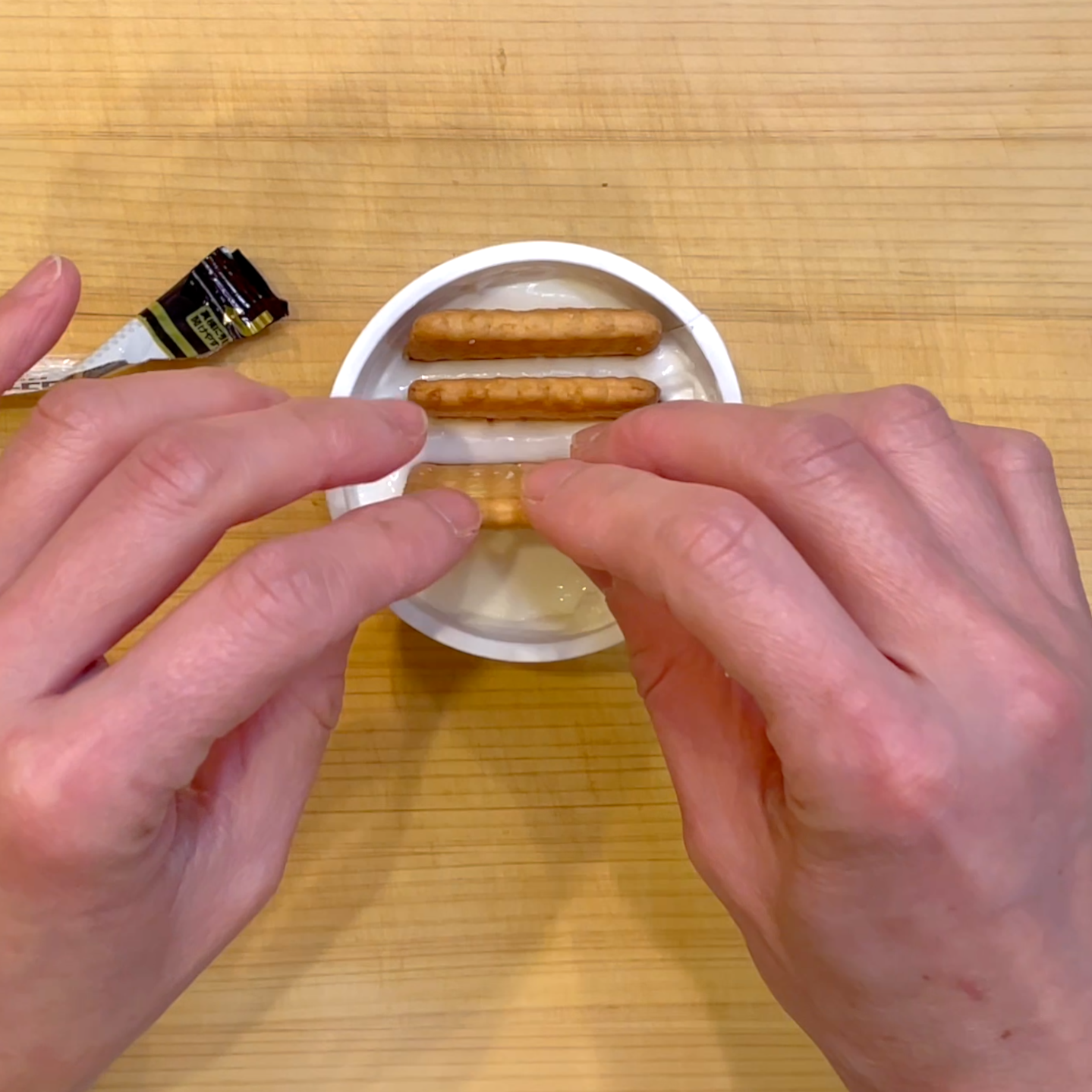 ヨーグルトにココナッツサブレを刺してラップをかけて冷蔵庫で冷やす工程